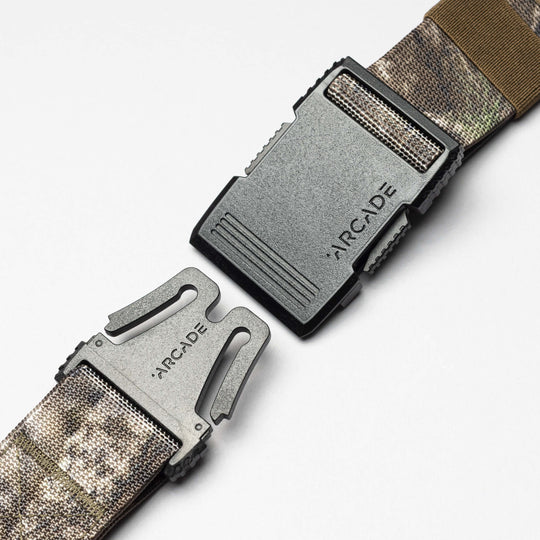 Two segments of the Arcade Belts Hardware low profile belt with a black plastic buckle, both engraved with the Arcade Belts name, are shown against a white background.