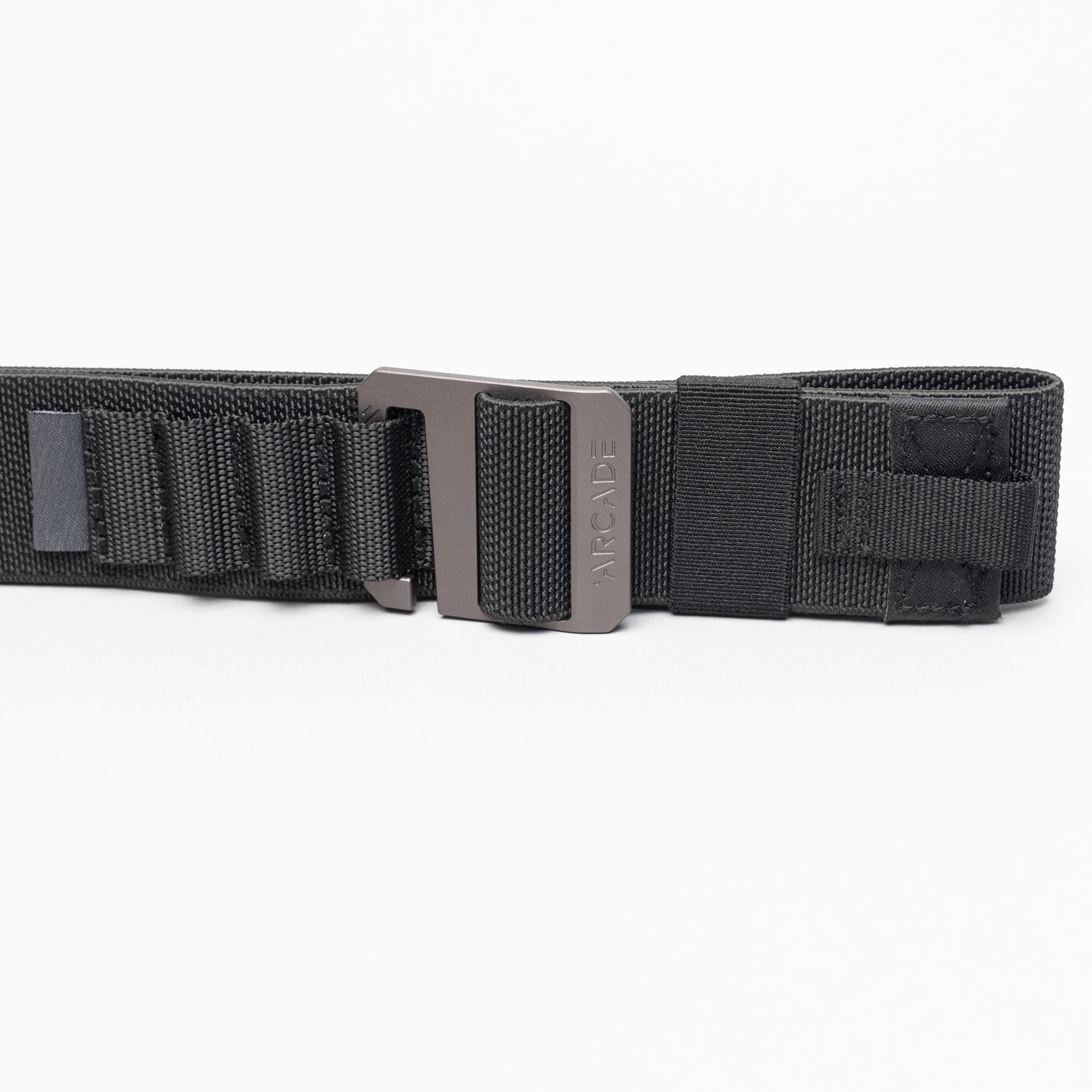 The Arcade Belts Hardware Alu is a black nylon low-profile belt with a metal buckle, shown on a white background. It features reinforced stitching and looped sections for extra durability, making it ideal for travel enthusiasts.