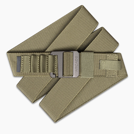 The Hardware Alu by Arcade Belts is an olive green stretch webbing belt with a black metal buckle, ARCADE branding, and reinforced stitching. Its low-profile, layered design makes it perfect for travel and daily use.