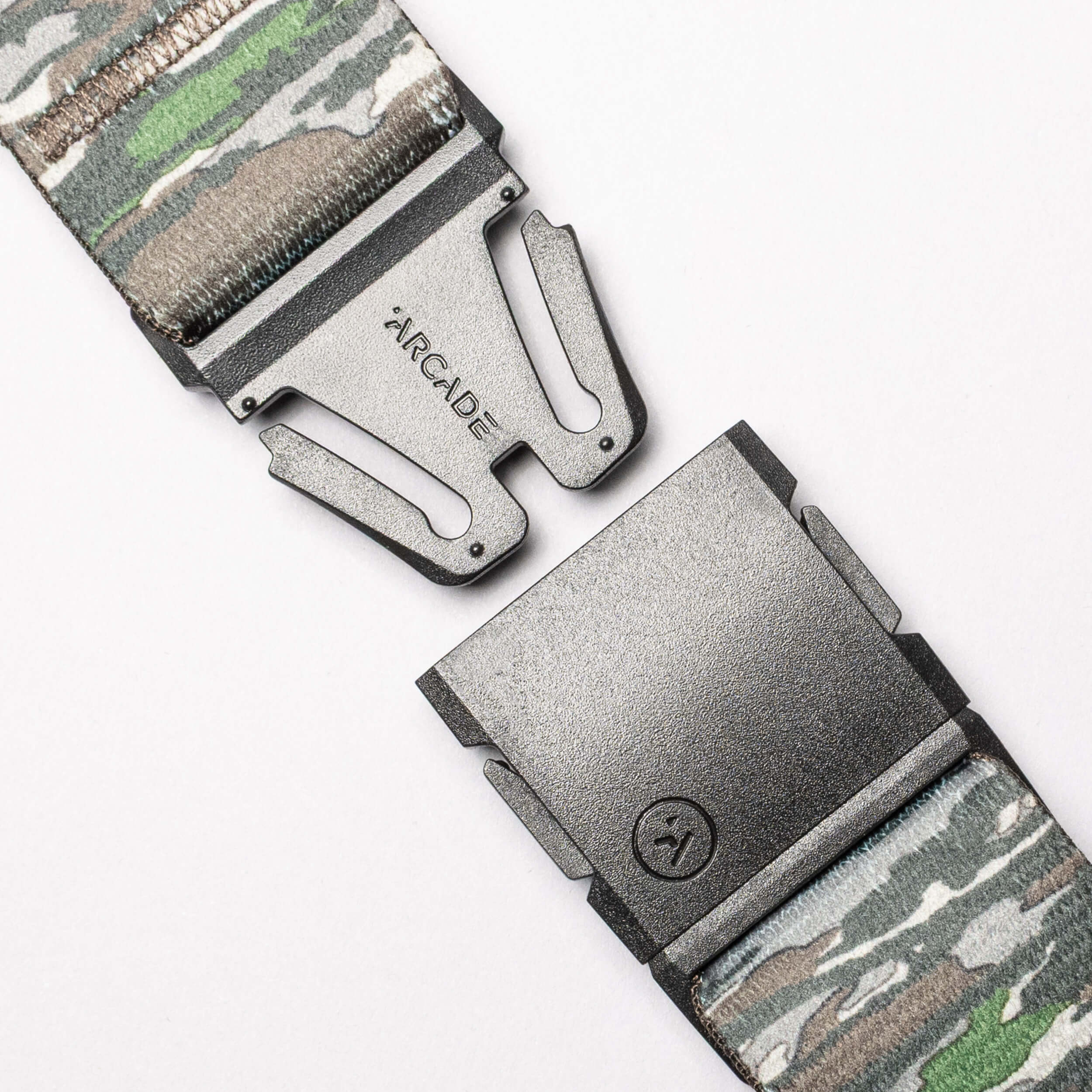 Close-up of the Realtree Camo Original by Arcade Belts, a stretch webbing belt with a camouflage pattern, partially open metal buckle engraved "ARCADE," and a small lower logo.